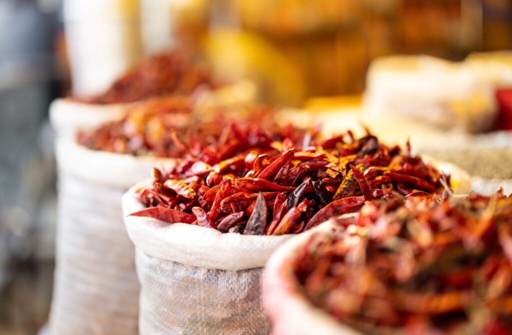 Close-up of bright red chili peppers in sacks, captured in an Indian marketplace setting, showcasing vibrant spices.